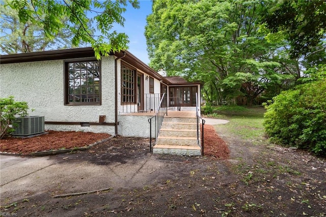 view of side of home featuring cooling unit and stucco siding
