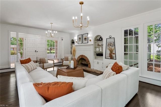 living area featuring dark wood-style flooring, an inviting chandelier, crown molding, and built in features
