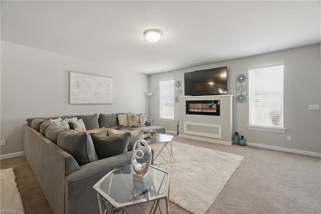 living area featuring carpet, visible vents, baseboards, and a glass covered fireplace