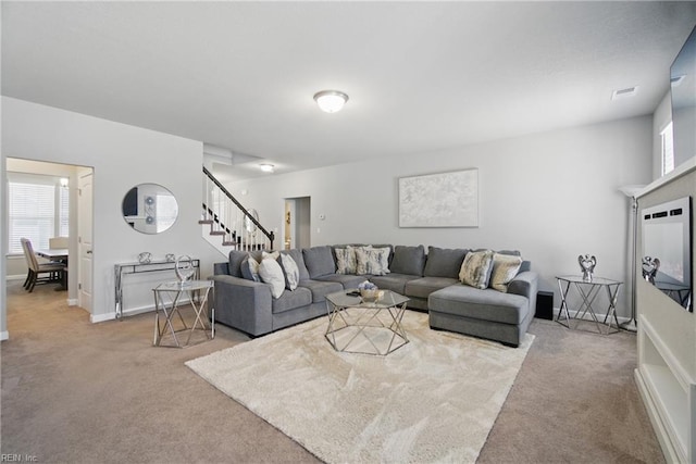 carpeted living room with baseboards, stairs, a healthy amount of sunlight, and visible vents