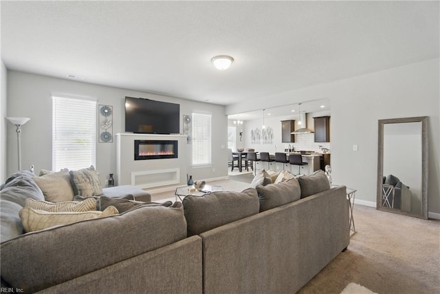 living room featuring light colored carpet, baseboards, and a glass covered fireplace