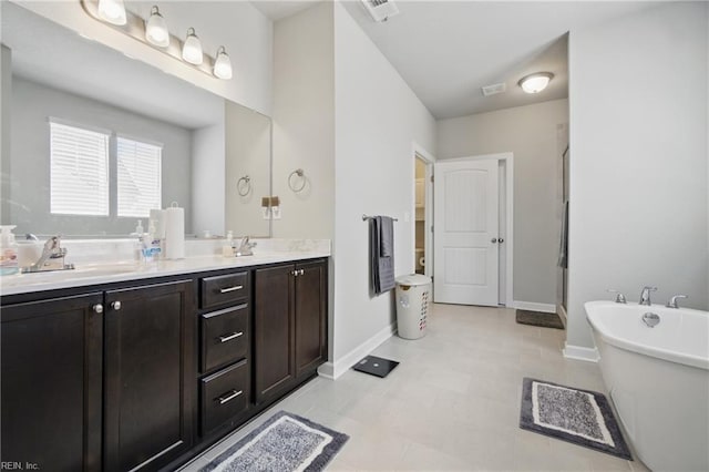 bathroom with baseboards, visible vents, a shower stall, a freestanding bath, and double vanity