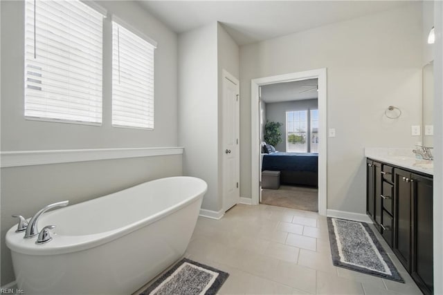 full bathroom with vanity, ensuite bathroom, a freestanding bath, and baseboards