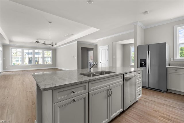 kitchen with appliances with stainless steel finishes, a sink, light wood finished floors, a kitchen island with sink, and crown molding