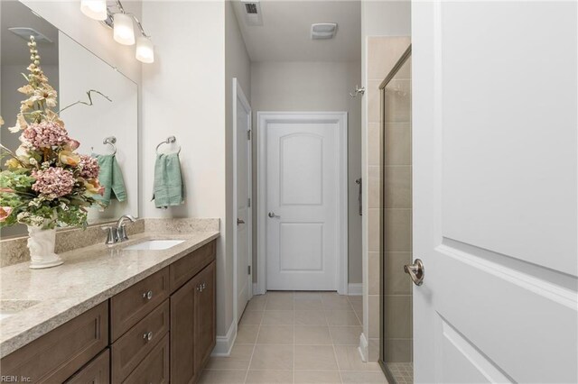 bathroom featuring a stall shower, tile patterned floors, double vanity, and baseboards