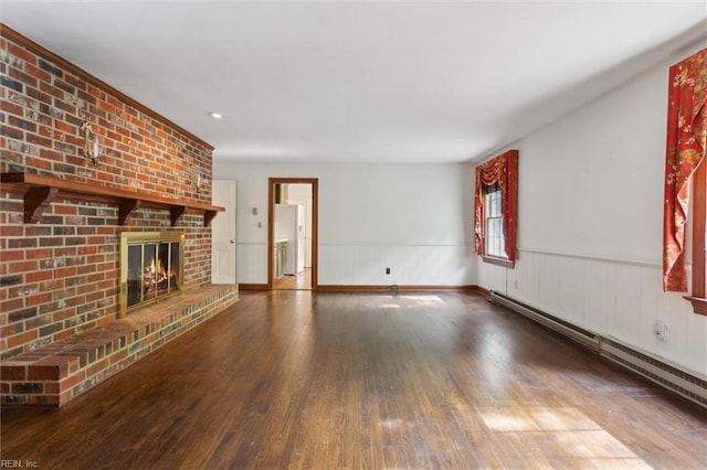unfurnished living room featuring a wainscoted wall, wood finished floors, a fireplace, and a baseboard heating unit