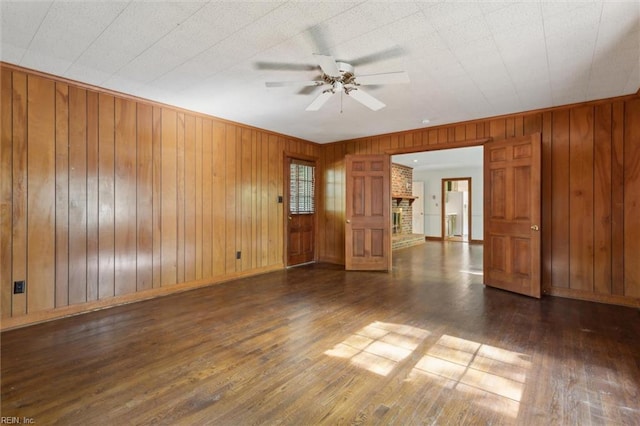 unfurnished room featuring ceiling fan, wooden walls, baseboards, and wood finished floors