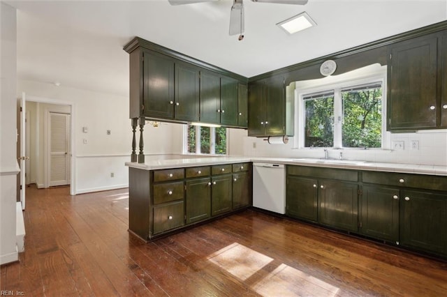 kitchen with a peninsula, dark wood-style flooring, light countertops, tasteful backsplash, and white dishwasher
