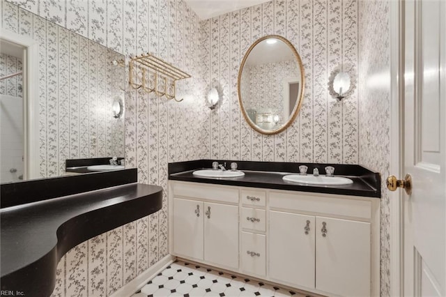 full bath featuring a sink, double vanity, and wallpapered walls