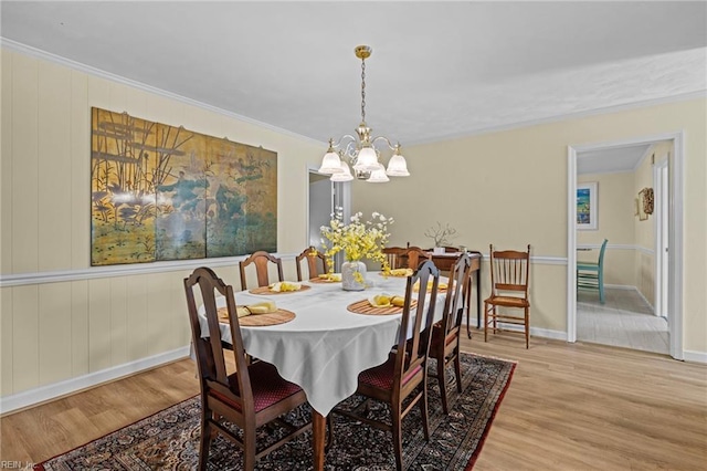 dining room with baseboards, crown molding, an inviting chandelier, and light wood-type flooring