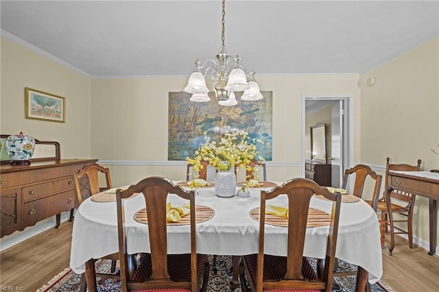 dining area featuring crown molding, a notable chandelier, a wainscoted wall, and wood finished floors