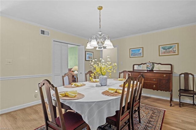 dining area featuring light wood-type flooring, visible vents, ornamental molding, and a notable chandelier