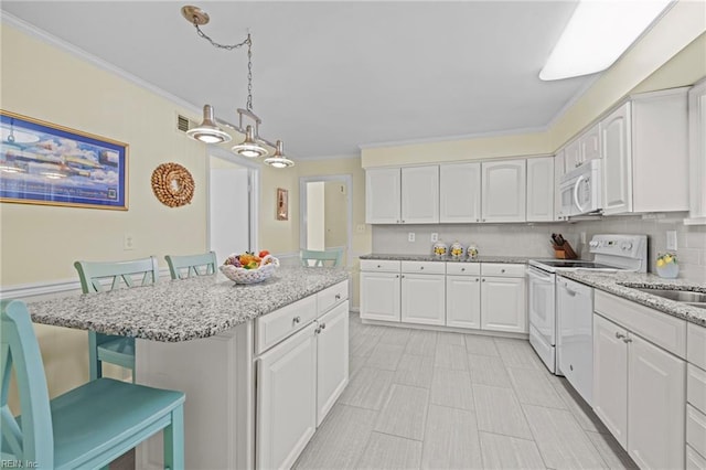 kitchen with white appliances, decorative light fixtures, ornamental molding, a kitchen breakfast bar, and white cabinets