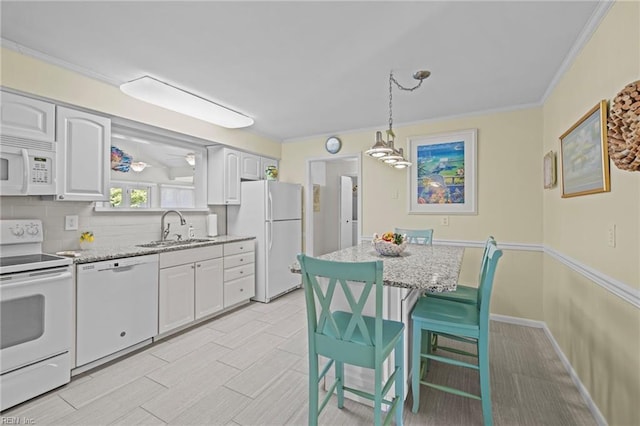 kitchen featuring a sink, white appliances, white cabinets, light stone countertops, and decorative light fixtures