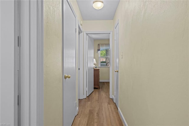 hall featuring light wood-style floors and baseboards