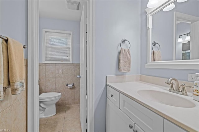 bathroom with tile walls, toilet, vanity, visible vents, and tile patterned flooring