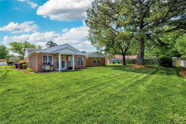 rear view of property featuring a yard, fence, and brick siding