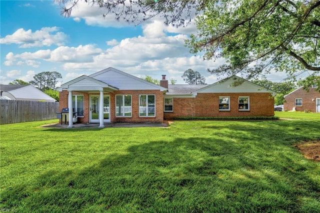 back of property featuring a yard, fence, and brick siding