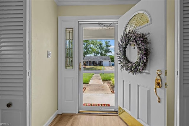 entryway featuring baseboards, light wood finished floors, and crown molding