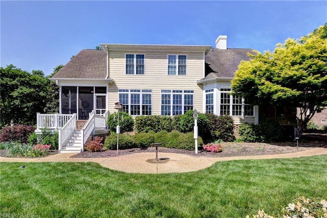 back of property with a sunroom, a yard, a chimney, roof with shingles, and stairs