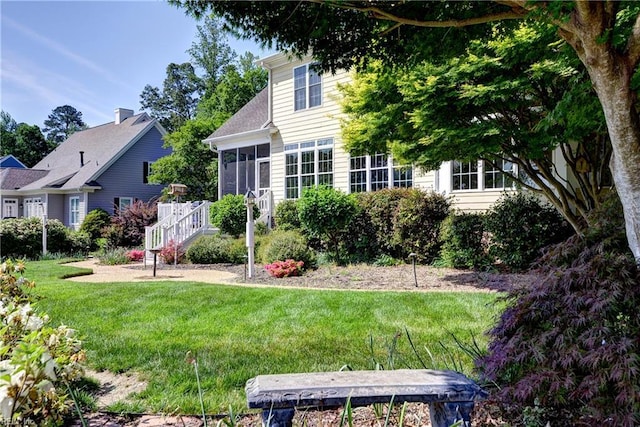 rear view of house featuring a lawn and a sunroom