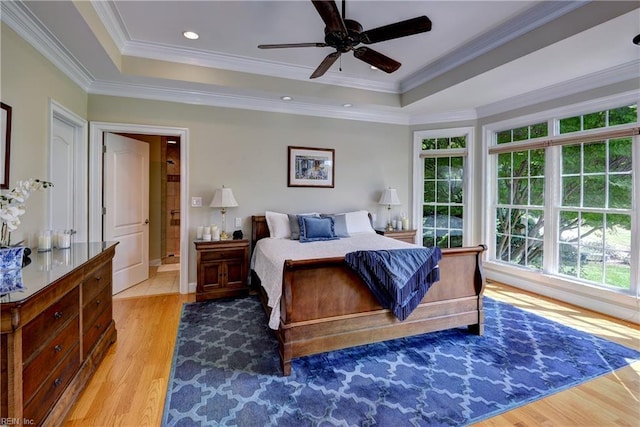 bedroom featuring a raised ceiling, wood finished floors, crown molding, and a ceiling fan