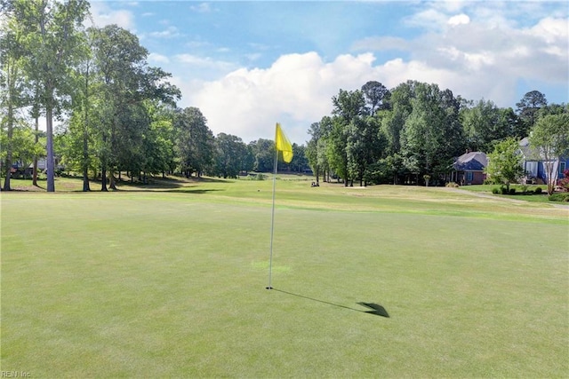 view of home's community featuring view of wooded area, a lawn, and view of golf course