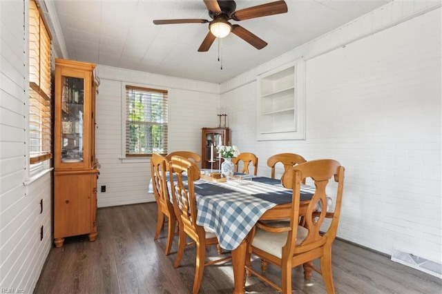 dining room with brick wall, ceiling fan, and wood finished floors