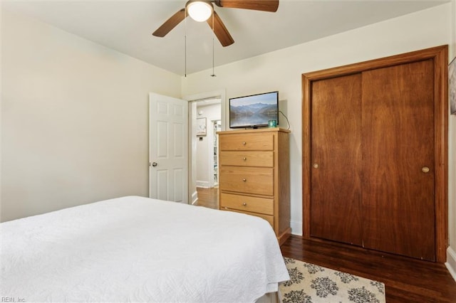 bedroom featuring a closet, baseboards, wood finished floors, and a ceiling fan