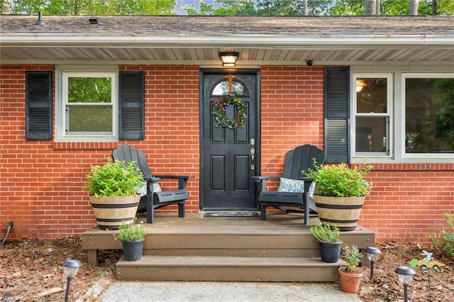 view of exterior entry with covered porch and brick siding