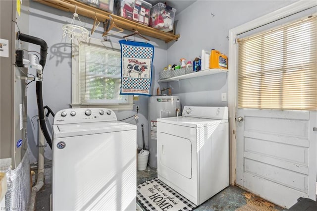 clothes washing area featuring washing machine and clothes dryer, laundry area, and water heater