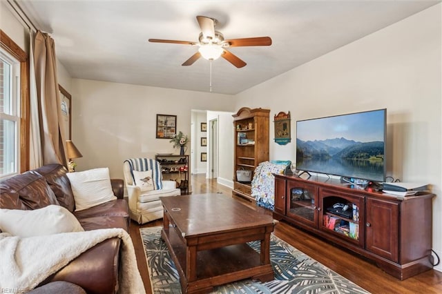 living room with a ceiling fan, baseboards, and wood finished floors