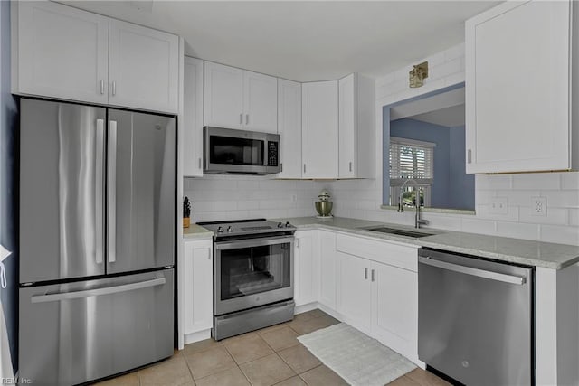 kitchen with light tile patterned floors, a sink, white cabinetry, stainless steel appliances, and tasteful backsplash