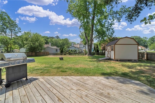 wooden terrace featuring a lawn, area for grilling, an outdoor structure, a storage shed, and a fenced backyard