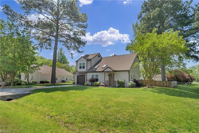 traditional home featuring a front yard, driveway, an attached garage, and fence