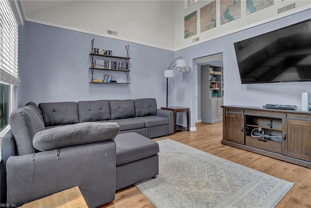 living area with visible vents, light wood-style flooring, and a high ceiling