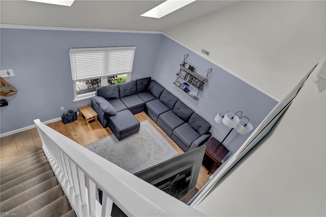 living room featuring lofted ceiling with skylight and baseboards