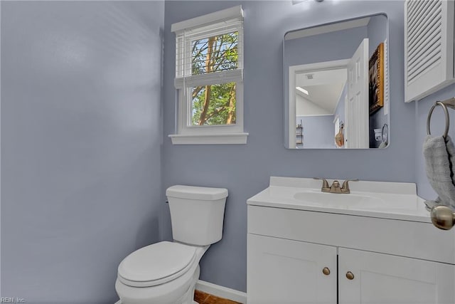 half bathroom with toilet, baseboards, and vanity