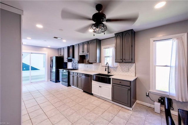 kitchen featuring light countertops, a sink, gas range oven, dishwasher, and tasteful backsplash