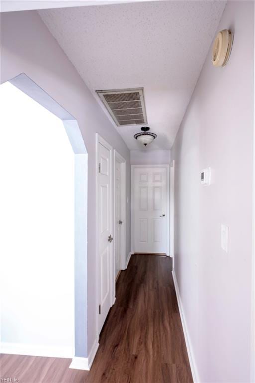 corridor with baseboards, visible vents, and wood finished floors