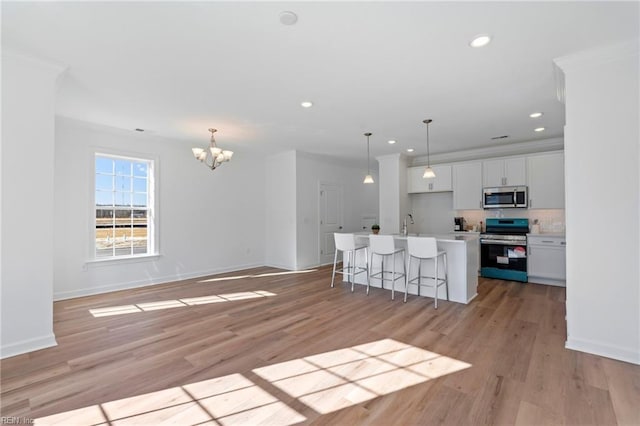 kitchen with a notable chandelier, recessed lighting, baseboards, a center island with sink, and appliances with stainless steel finishes