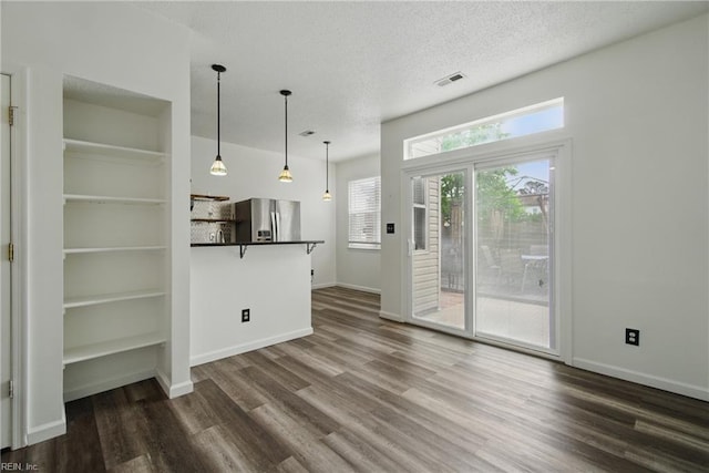 unfurnished living room featuring a textured ceiling, visible vents, baseboards, and dark wood-type flooring