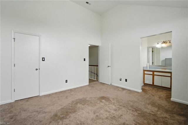 unfurnished bedroom featuring baseboards, ensuite bathroom, high vaulted ceiling, and carpet floors
