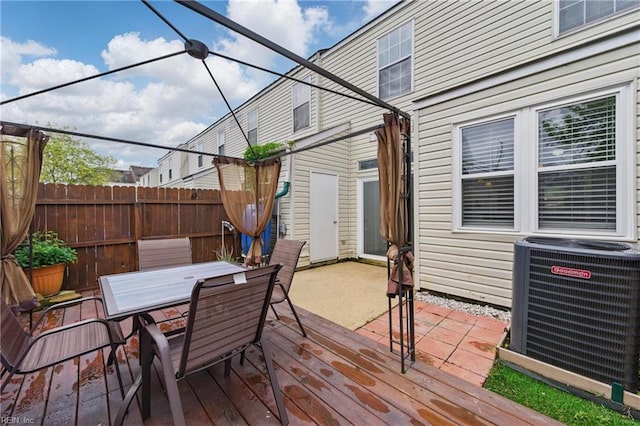 wooden deck with outdoor dining space, fence, and cooling unit