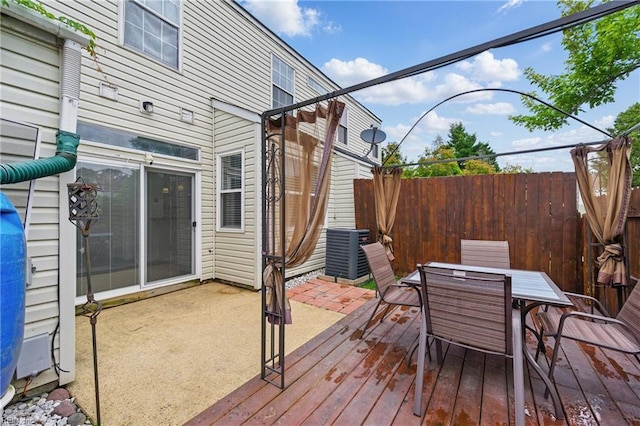 wooden deck with central air condition unit, fence, and outdoor dining space