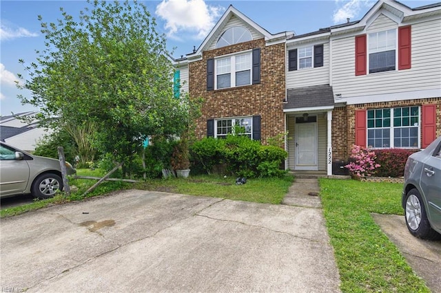 view of property with brick siding and a front yard