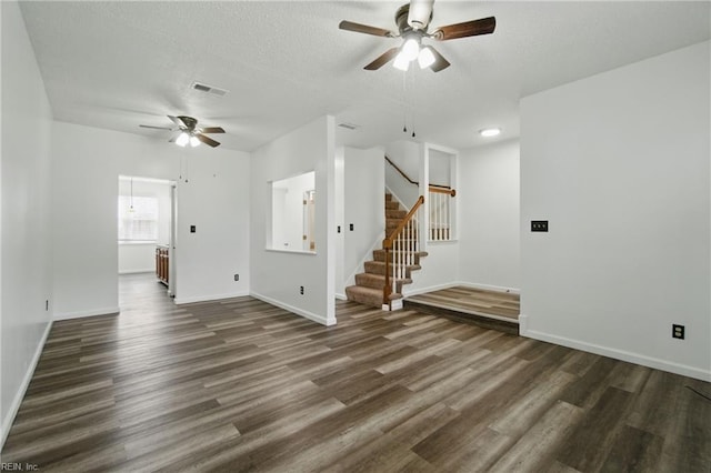 unfurnished living room with baseboards, a ceiling fan, dark wood-type flooring, and visible vents