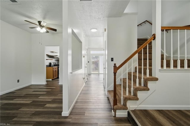 entrance foyer featuring a ceiling fan, a textured ceiling, baseboards, stairs, and dark wood-type flooring