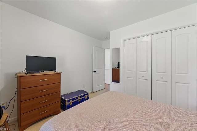 bedroom featuring light colored carpet, a closet, and baseboards