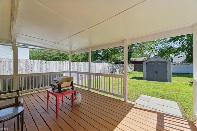 wooden deck with a fenced backyard, an outdoor structure, a shed, and a lawn